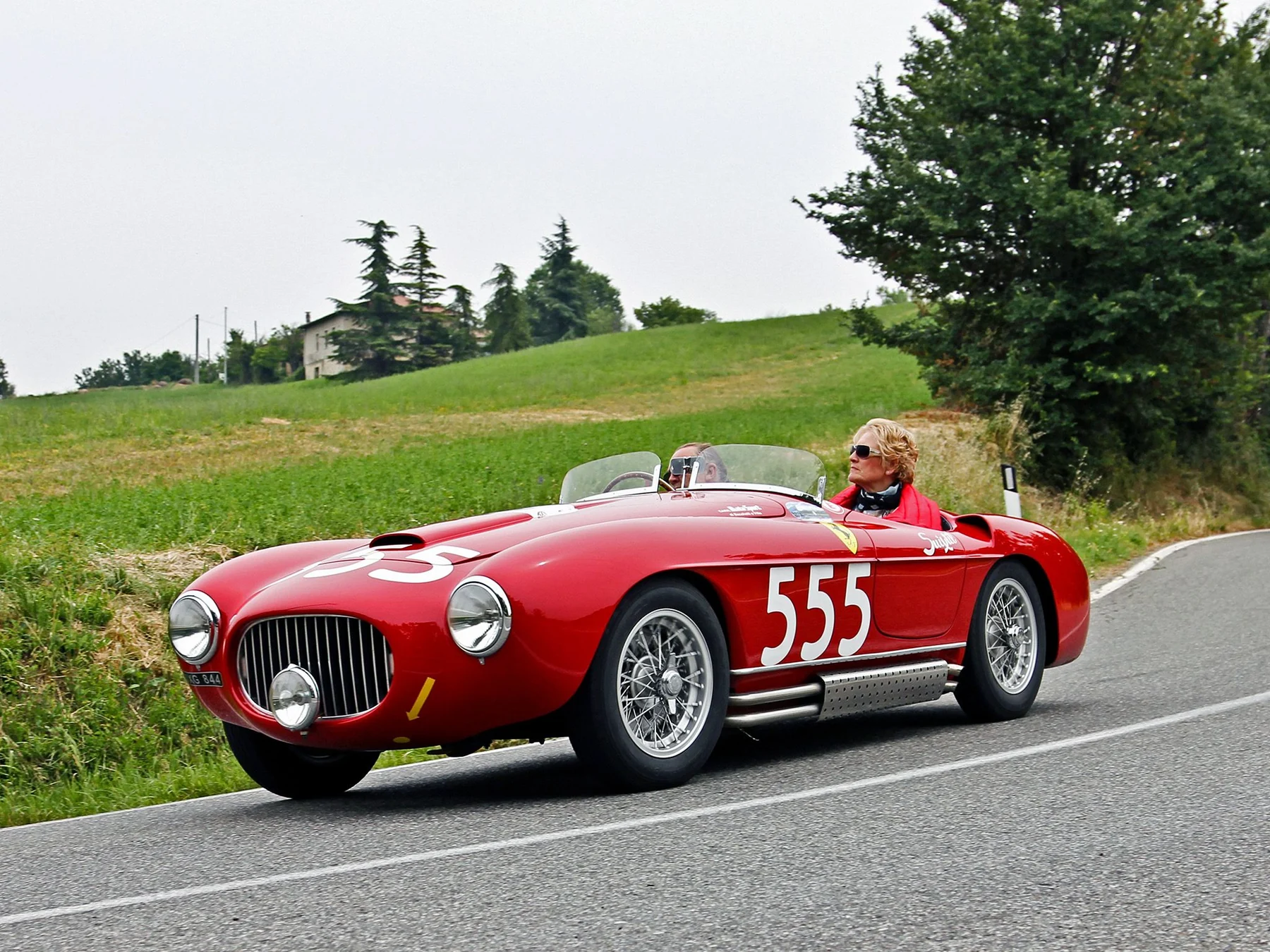 Historic red Ferrari number 555 driving on an Italian road